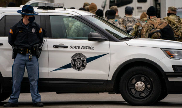 A member of the Washington State Patrol guards an entrance as Washington National Guard personnel w...