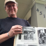 David Christensen on the porch of an old house in Wallingford, with a book showing Seattle Rainiers broadcaster Leo Lassen standing near the same spot 50 years earlier.  Late former KIRO Radio sportscaster Wayne Cody is also pictured in the book; he produced a tribute album about Leo Lassen in 1976. (Feliks Banel)