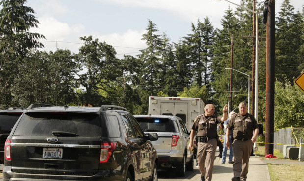 Officials with the Thurston County Sheriff's Office walk in a neighborhood where a shooting left mu...