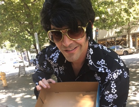 A Seattle Elvis impersonator poses with a box of Bacon Maple Elvis Bar doughnuts....