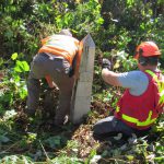 International Boundary Commission representatives inspect a boundary monument in the foothills of the Cascade Mountains.  (Photo courtesy International Boundary Commission)