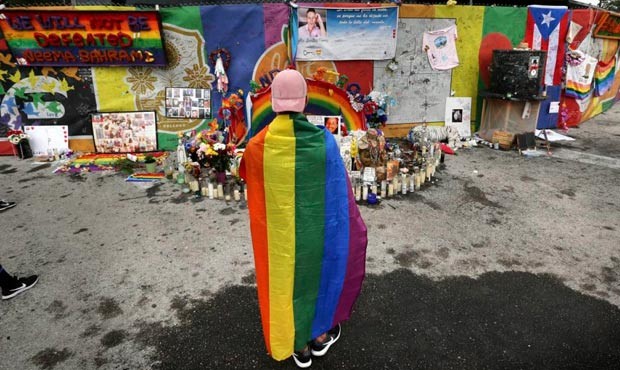 A runner wearing a gay pride rainbow flag pauses in front of the Pulse nightclub during the CommUNI...