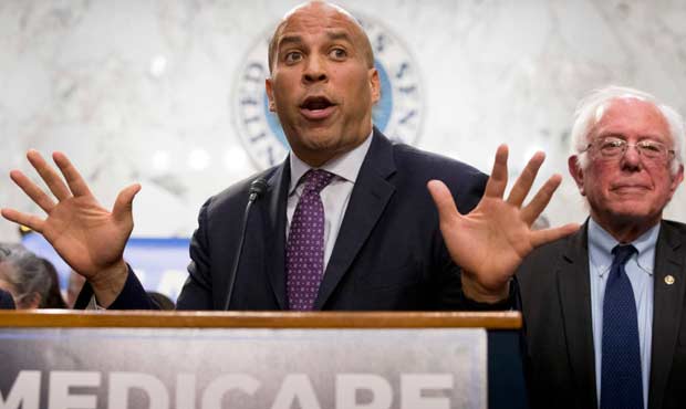 Sen. Cory Booker, D-N.J., left, accompanied by Sen. Bernie Sanders, I-Vt., right, speaks during a n...