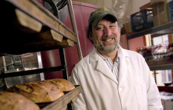 Essential Baking Company's founder, George De Pasquale, stands next to some of his fresh baked, cru...