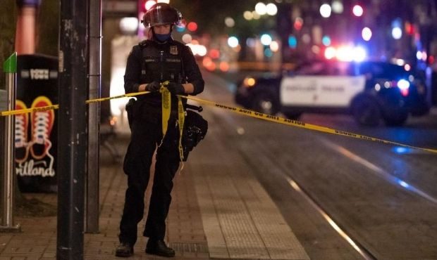A Portland police officer ties a police line around the scene of a fatal shooting on August 29, 202...