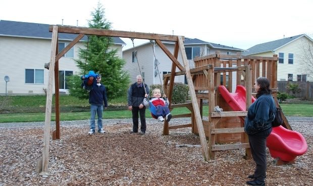 Josh Powell and Chuck Cox push Charlie and Braden on swings as Judy Cox looks on, Feb. 27, 2010, in...
