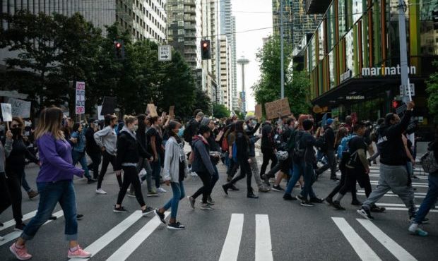 Black Lives Matter protesters march through a downtown street on June 14, 2020 in Seattle, United S...