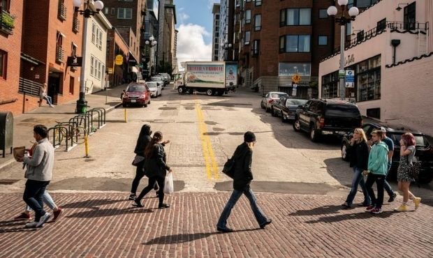 Pedestrians cross the street as Seattle has become the first major city to reach a 70 percent COVID...
