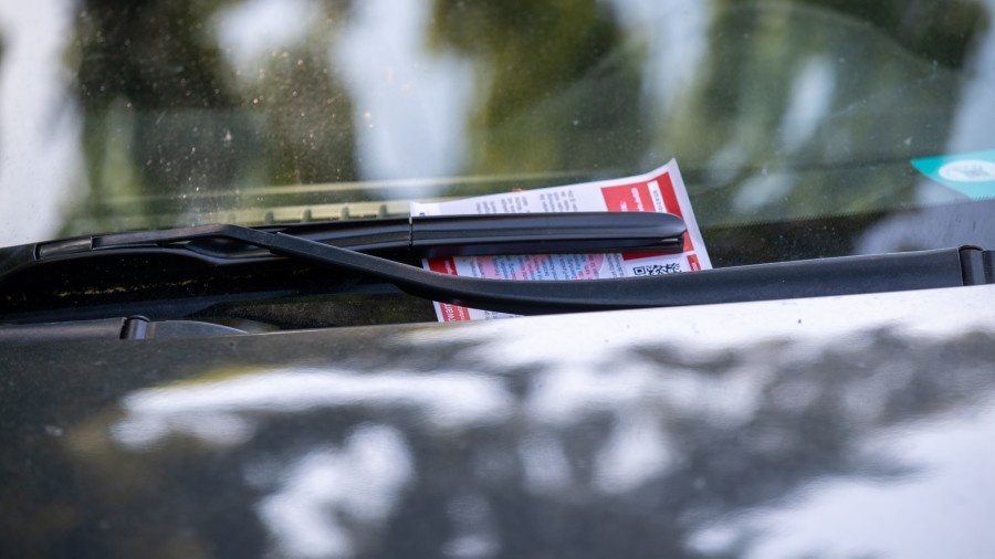 A car is parked in a parking zone with a parking ticket on the windshield wiper.  (Photo by Daniel ...