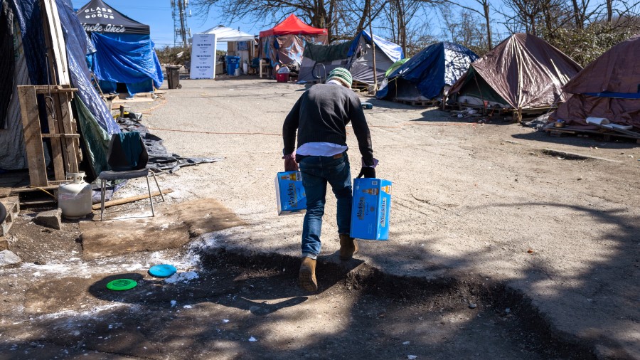 A man brings shoplifted beer to sell at a homeless encampment on March 12, 2022 in Seattle, Washing...