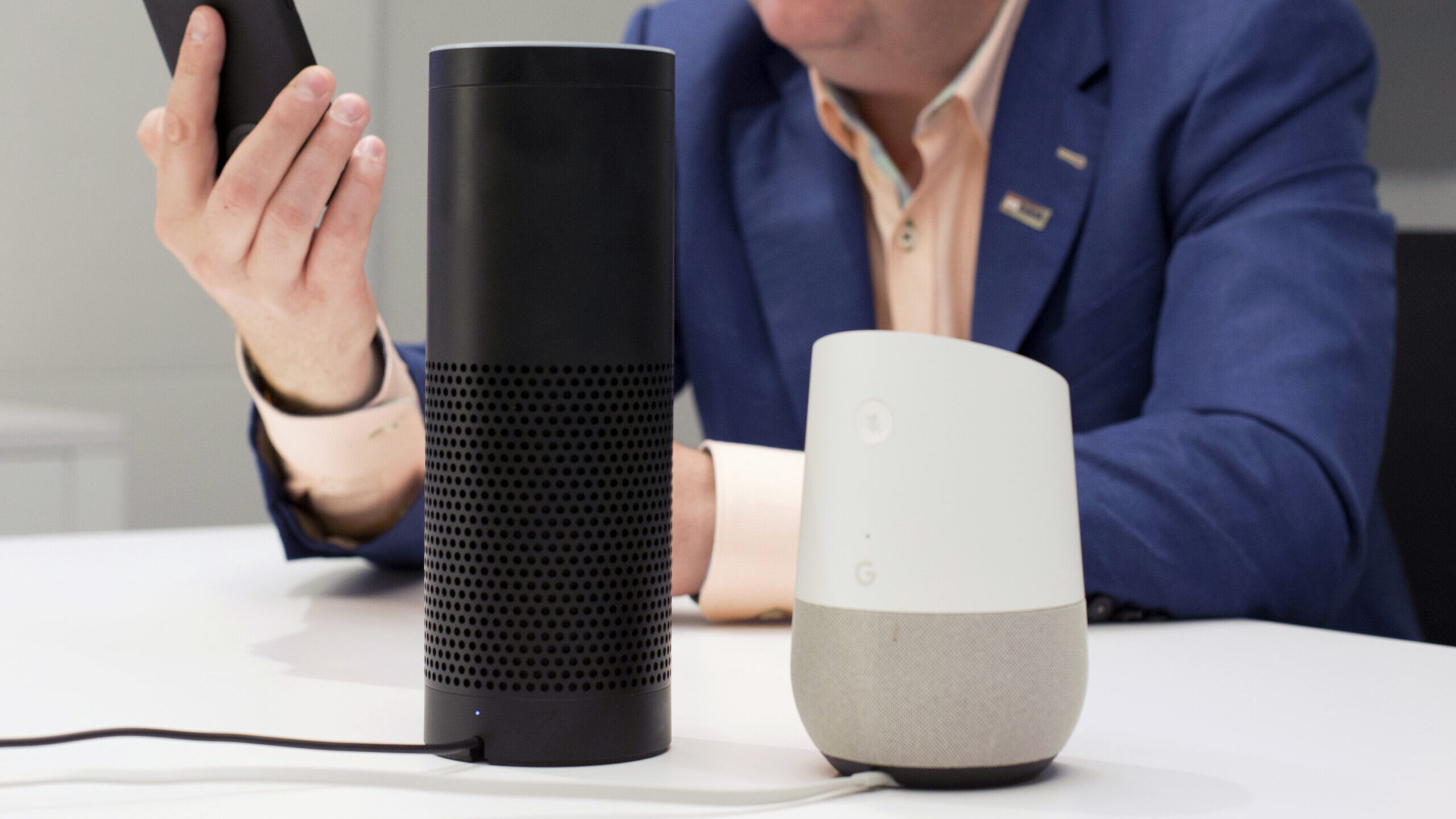 A man holds an iPhone next to an Amazon Echo, center, and a Google Home, right, in New York on June...