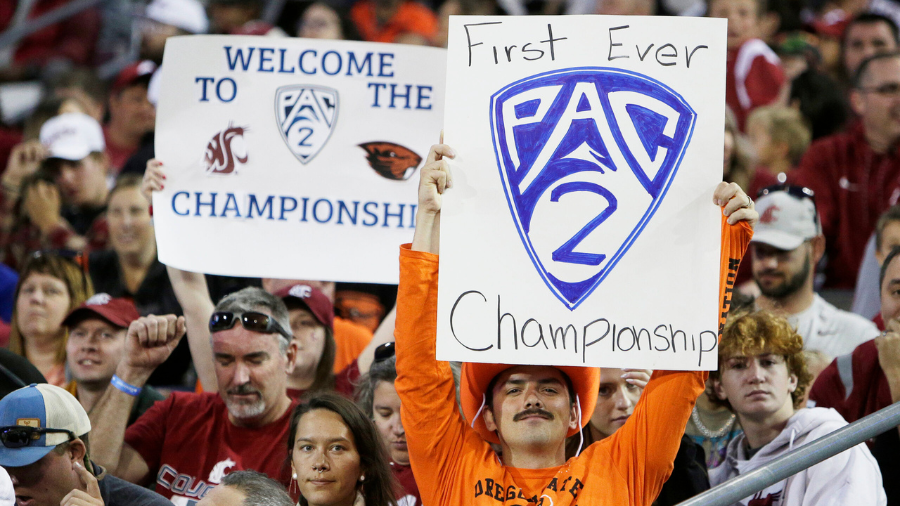 Image: An Oregon State fan, front, and a Washington State fan hold "Pac-2" signs, representing the ...