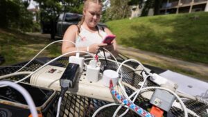 Photo: Carrie Owenby looks at her phone as a neighbor with power dropped an extension cord for neighbors who have no power in the aftermath of Hurricane Helene, Monday, Sept. 30, 2024, in Asheville, N.C.