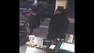 Photo: Masked suspect points a firearm during one of the robberies.