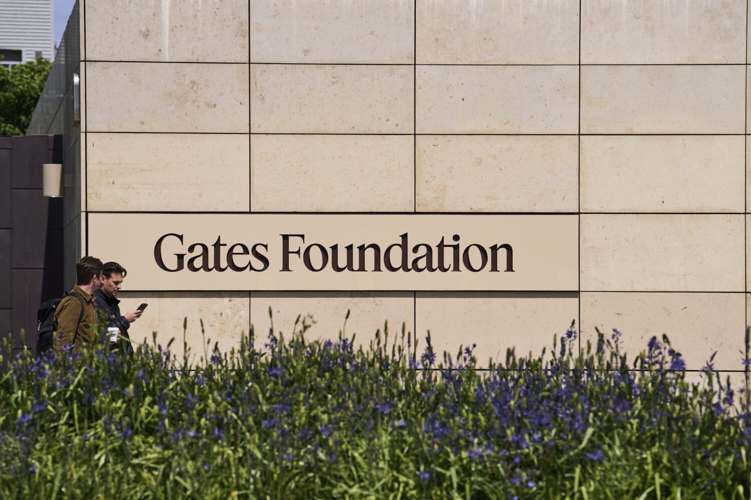 People walk by a Gates Foundation sign at the foundation's campus Wednesday, April 30, 2025, in Sea...