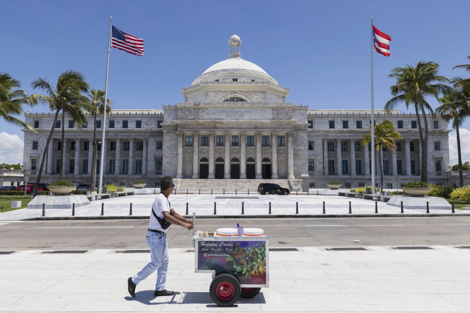 An ice cream vendor pushes his cart past Puerto Rico's Capitol building in San Juan, Puerto Rico, T...
