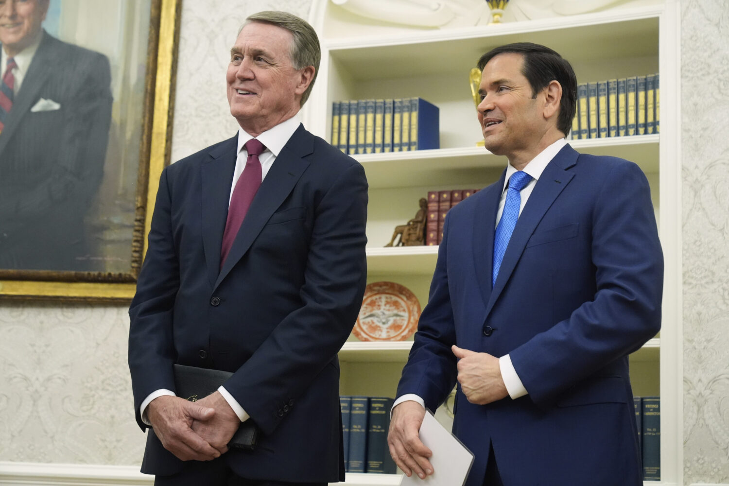 David Perdue and Secretary of State Marco Rubio listen as President Donald Trump speaks before Perd...