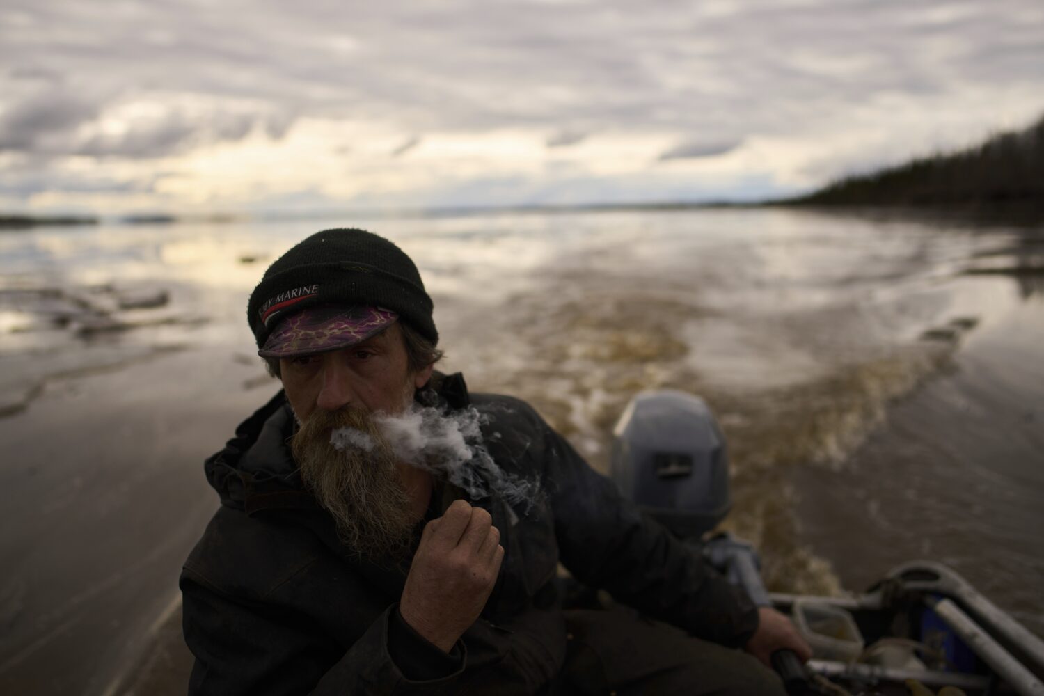 Jake Pogrebinsky smokes a cigarette while diving his boat on the Yukon River looking for logs to co...
