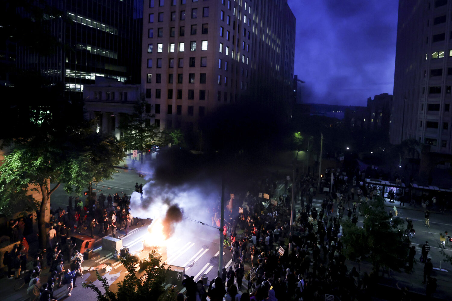 Protestors surround a dumpster that was set on fire in front of the Henry M. Jackson Federal Buildi...