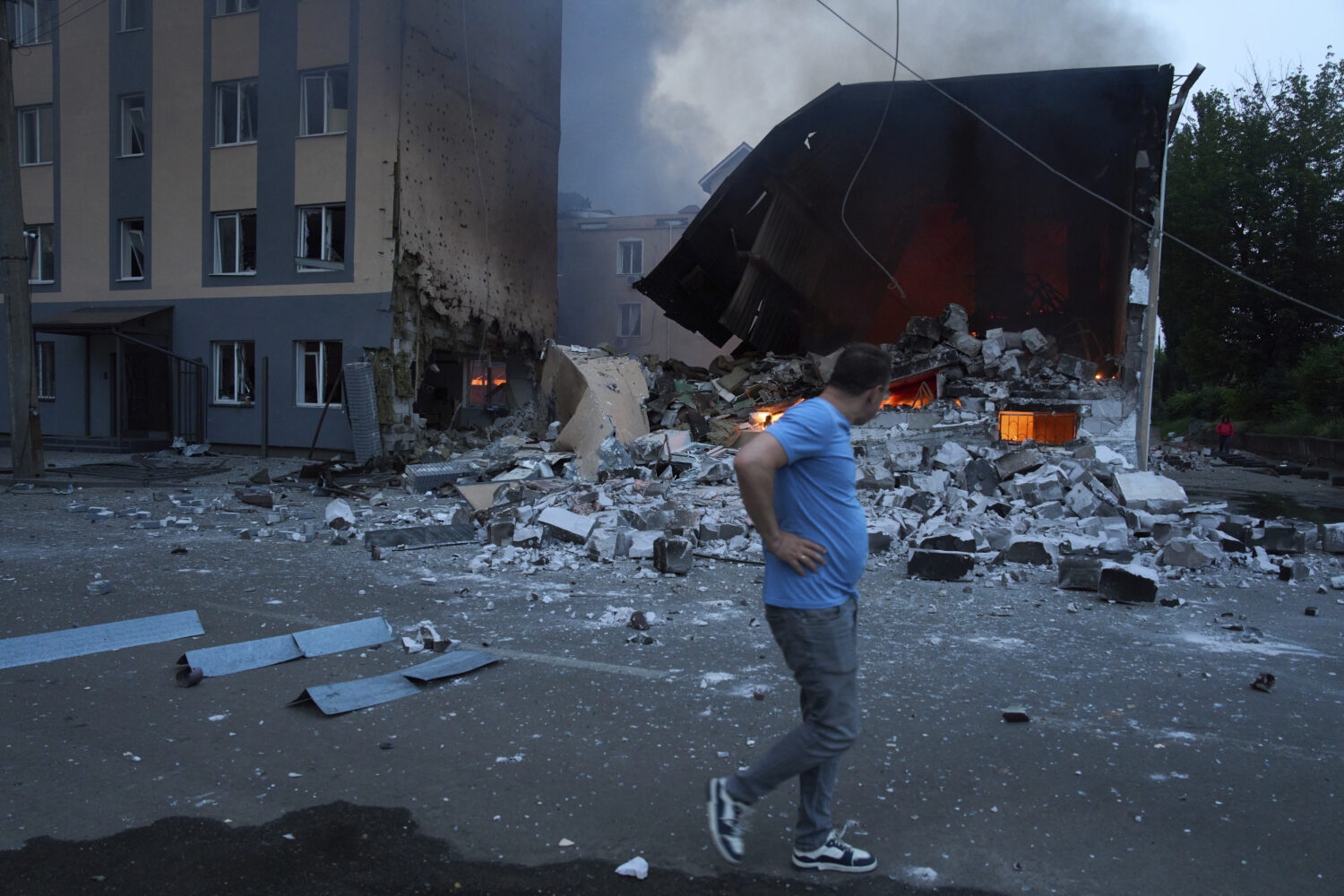 A resident reacts as he passes by burning debris following Russia's missile and drone attack in Kyi...