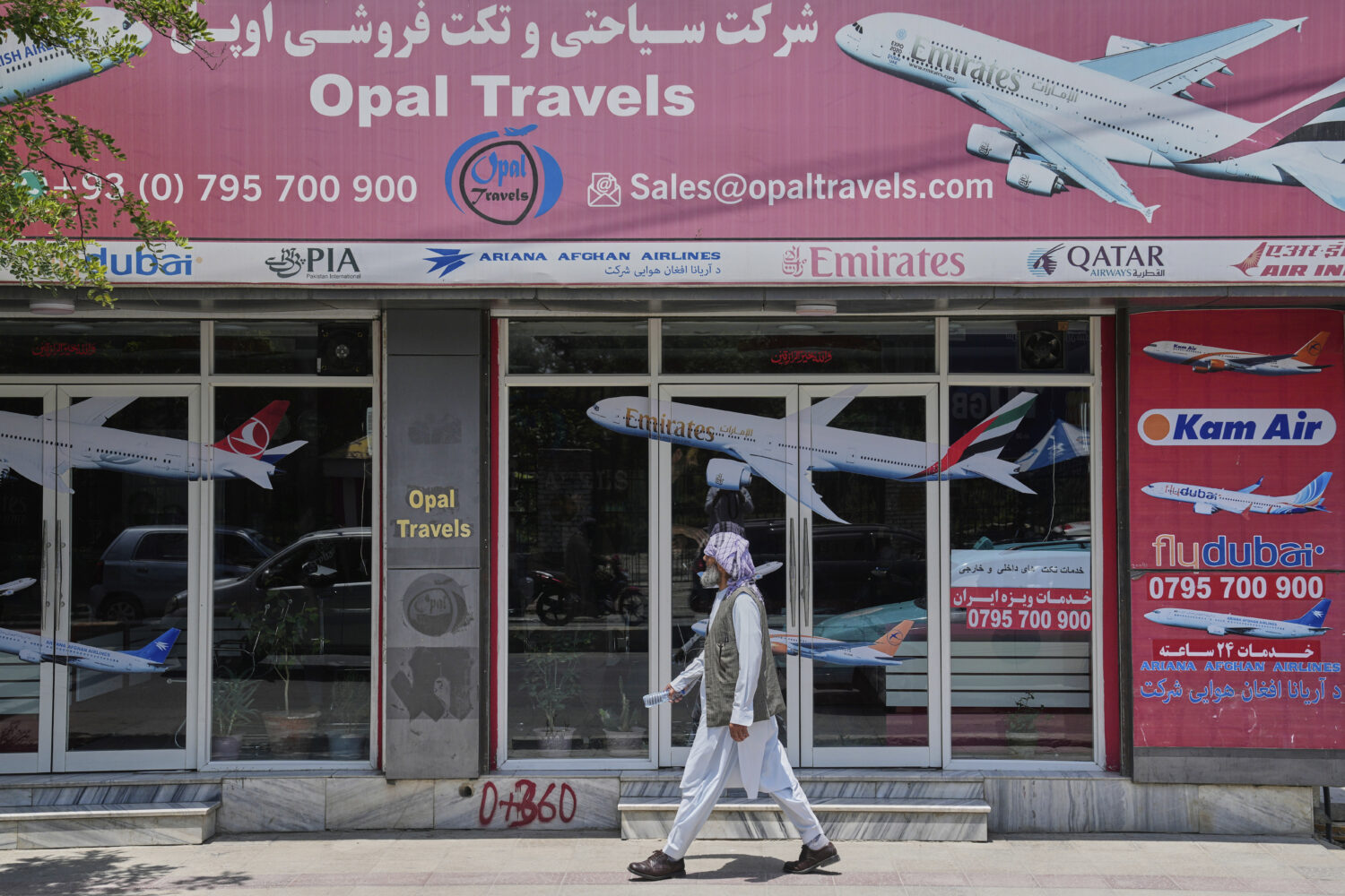 An Afghan person passes in front of an air travel agency in Kabul, Afghanistan, Thursday, June 5, 2...