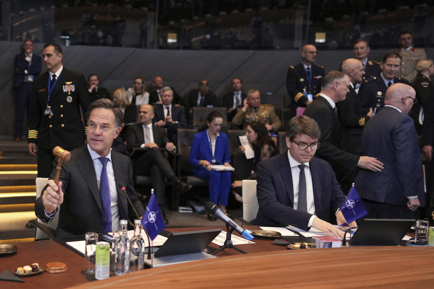 NATO Secretary General Mark Rutte, left, bangs a gavel to signify the start of a meeting of NATO de...