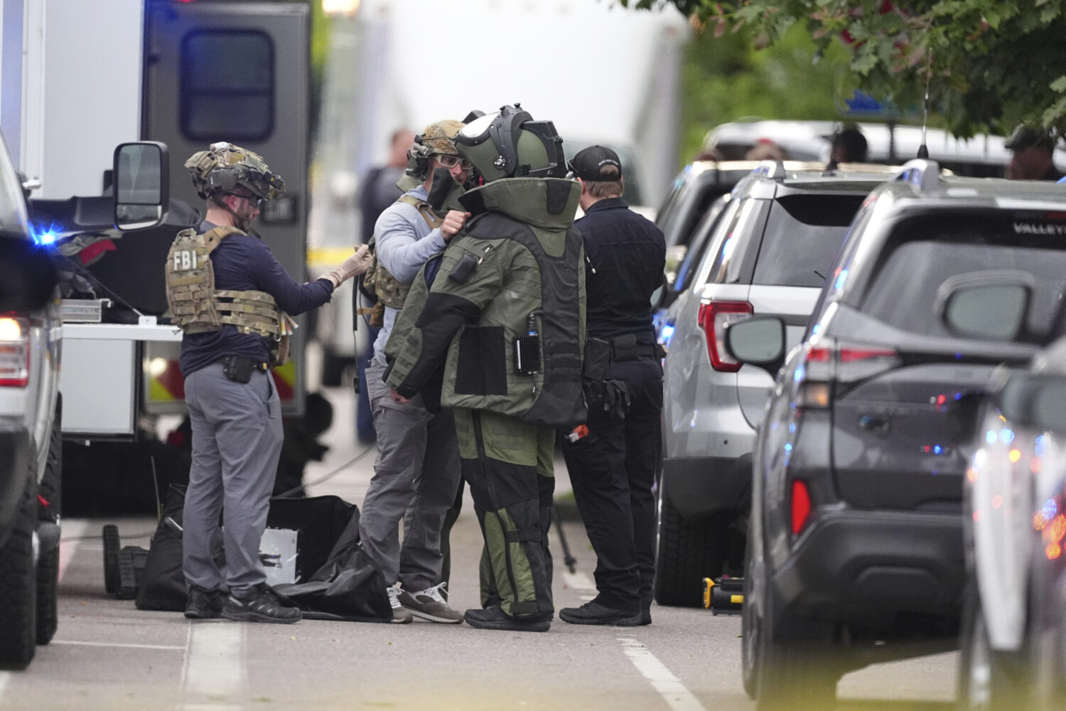 Law enforcement officials dress up in protective gear to investigative an attack on the Pearl Stree...