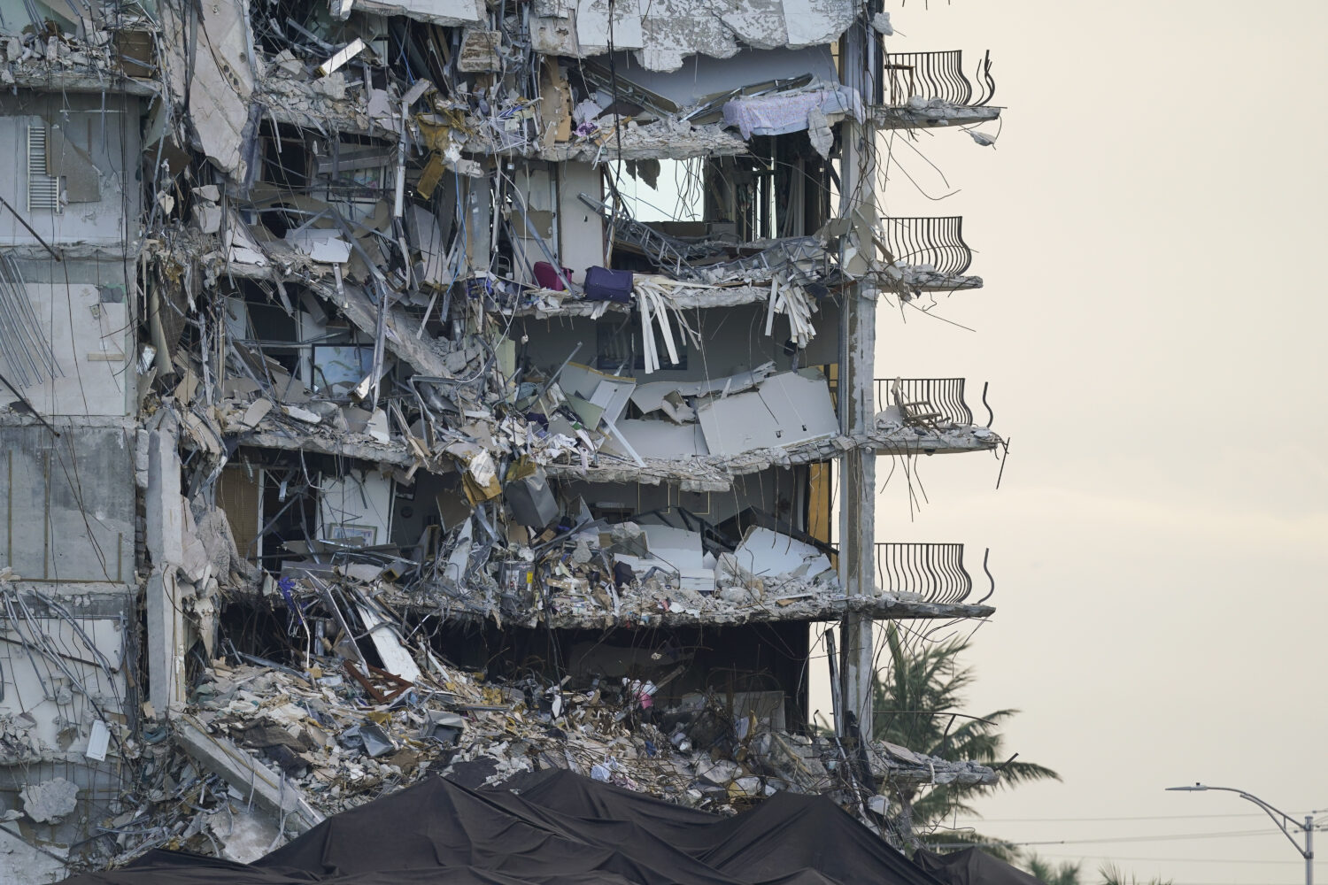 FILE - A giant tarp, bottom, covers a section of rubble at the Champlain Towers South condo buildin...
