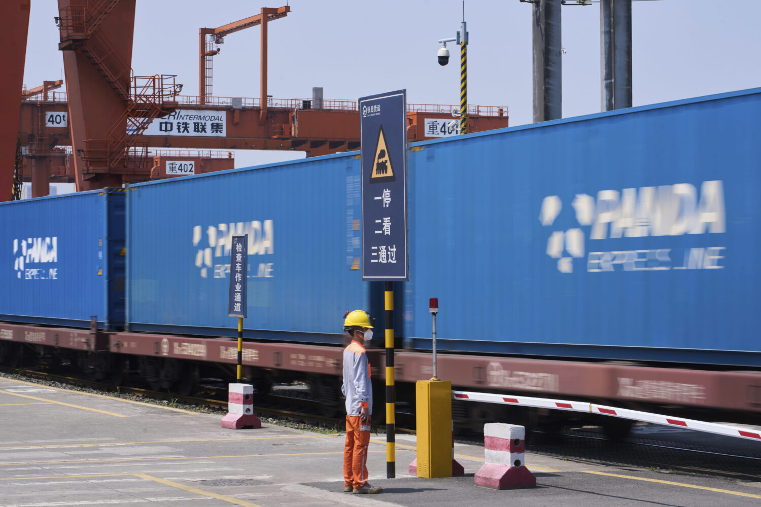 A worker stands watch as a train loaded with containers leaves the Chongqing Railway Container Term...