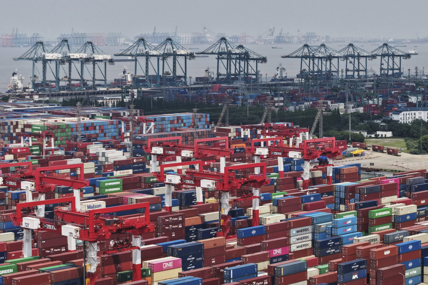 Trucks loaded with container move through a container terminal port in Shanghai, China Monday, June...