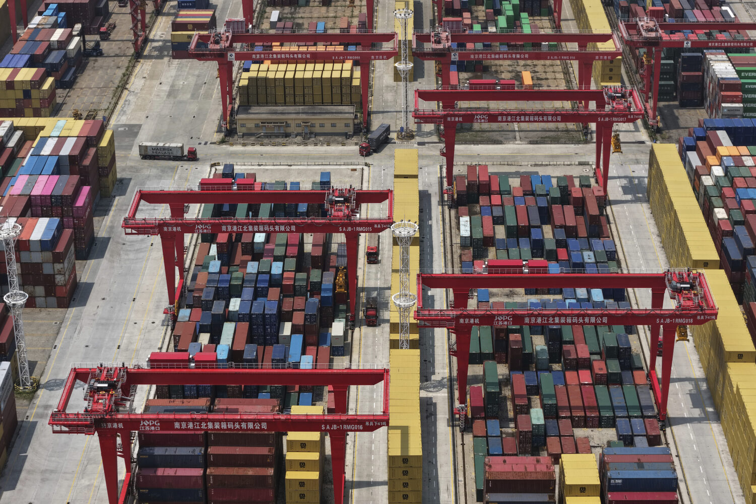 Trucks move through containers piled up at a container terminal in Nanjing in east China's Jiangsu ...