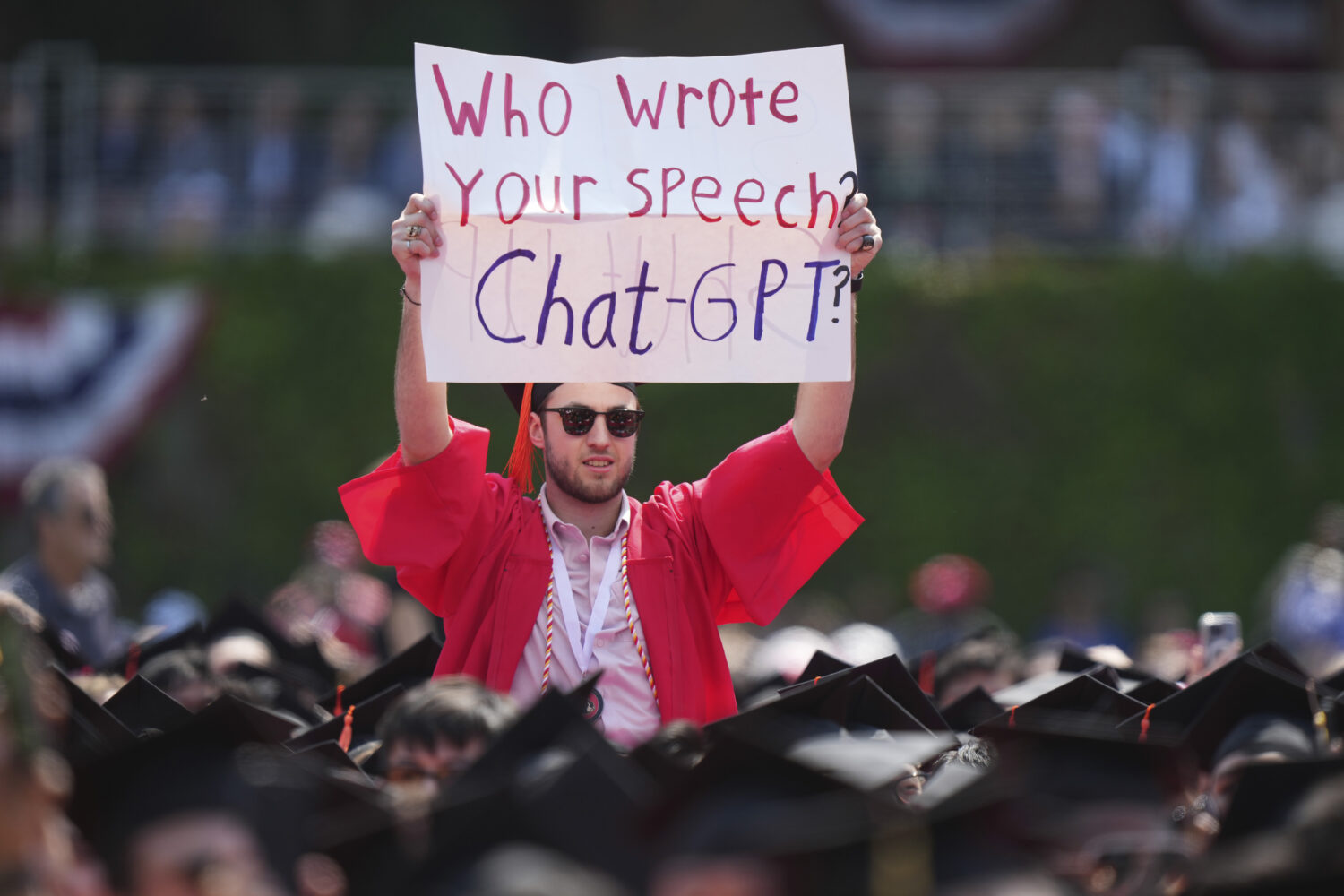 FILE - A person in a graduation cap and gown holds a sign during an address by David Zaslav, presid...