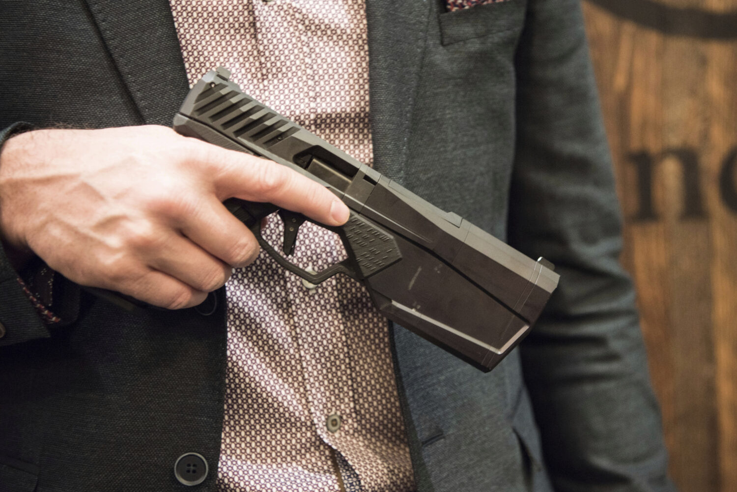 FILE - Josh Waldron, co-founder and CEO of SilencerCo, holds a 9mm handgun with a suppressor embedd...