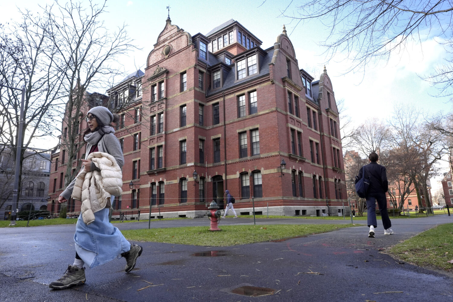 FILE - People walk between buildings, Dec. 17, 2024, on the campus of Harvard University in Cambrid...