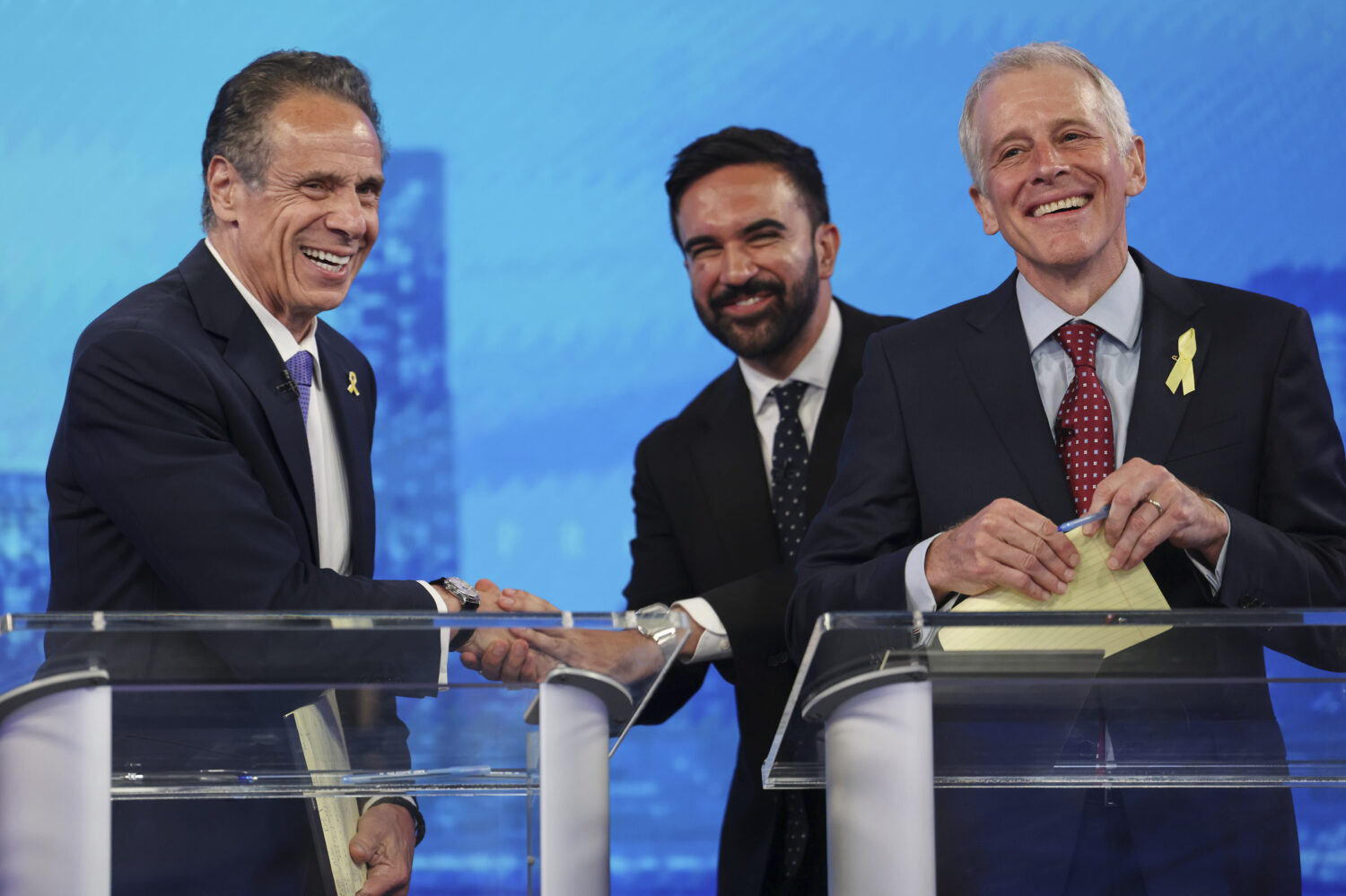 Democratic mayoral candidates Andrew Cuomo, left, shakes hands with Zohran Mamdani, center, as Whit...