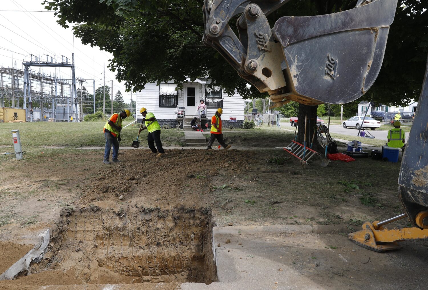 FILE - Workers back fill a hole used to replace lead pipe with copper water supply lines to a home ...