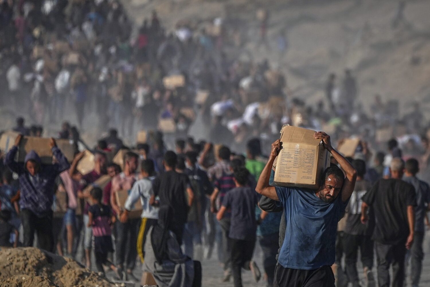 Palestinians carry sacks and boxes of food and humanitarian aid unloaded from a World Food Program ...