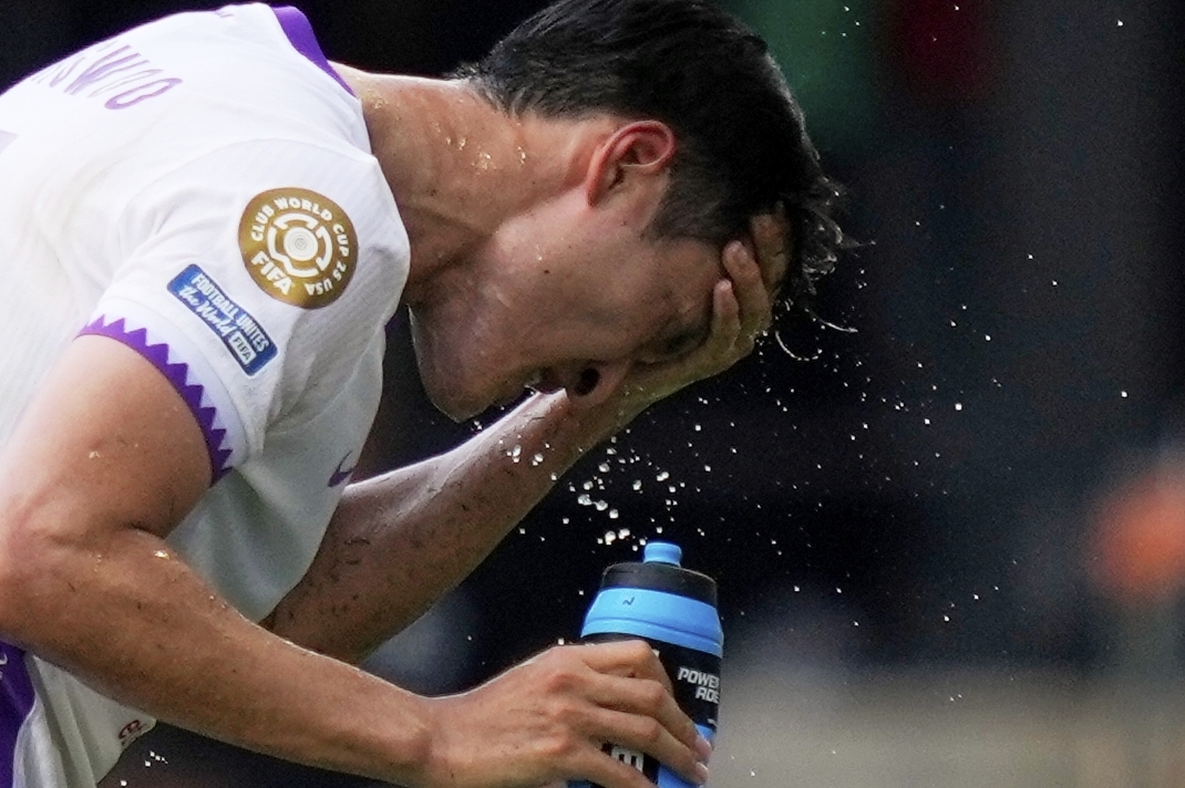 Al Ain's Park Yong-woo splashes his face to cool off during the Club World Cup Group G soccer match...