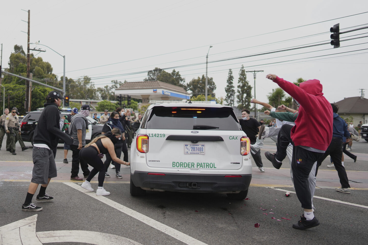 Protesters kick the side of a Border Patrol vehicle during a demonstration over the dozens detained...