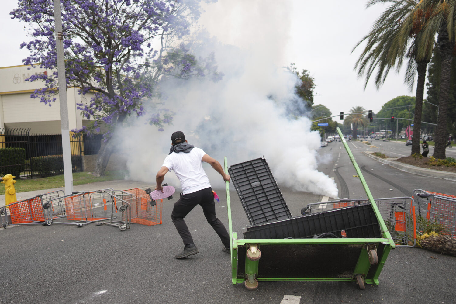 A protester looks on as Border Patrol personnel in riot gear and gas masks stood guard outside an i...