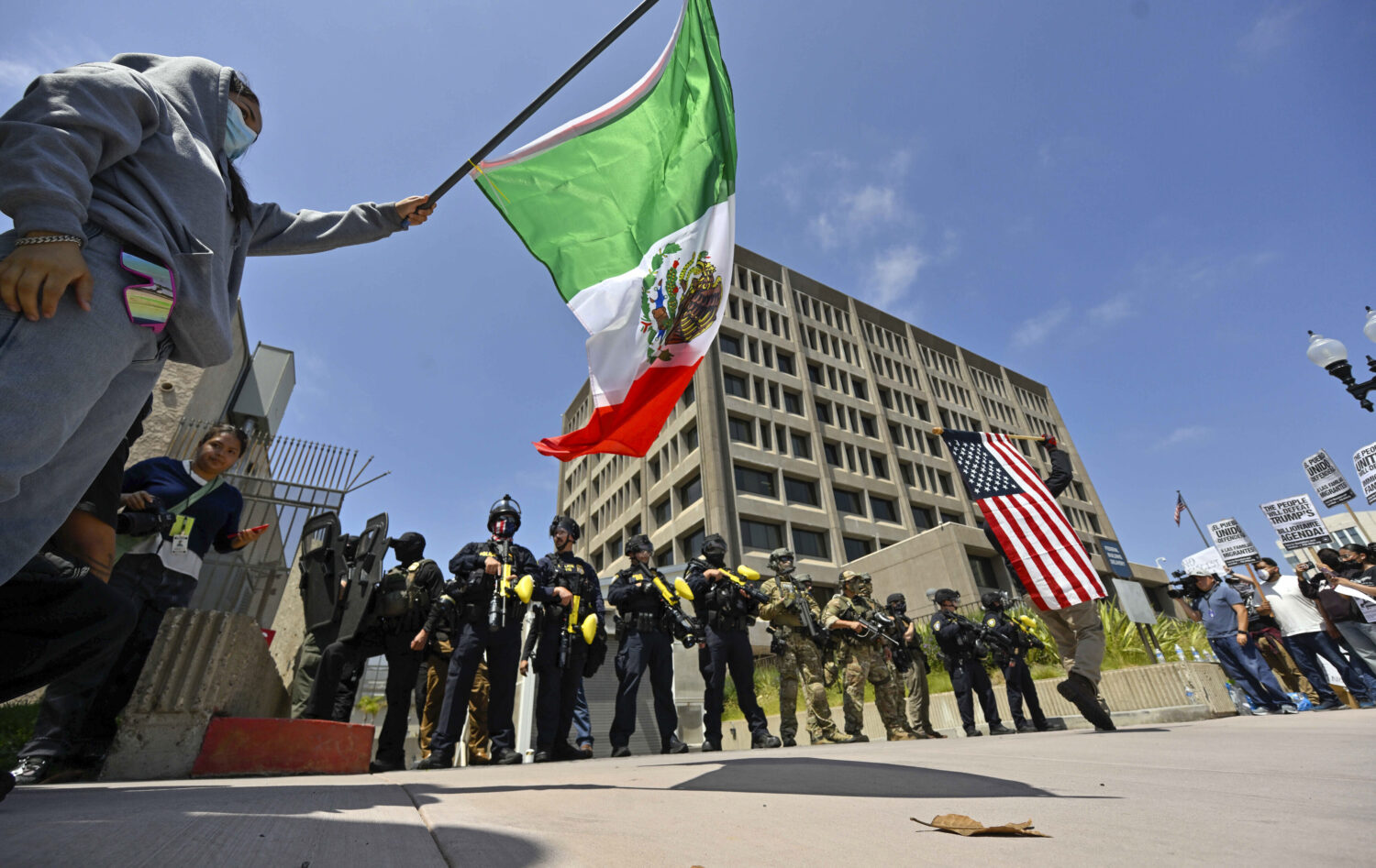 Protesters block the driveway to the Federal Building as police stand guard in Santa Ana, Calif., o...