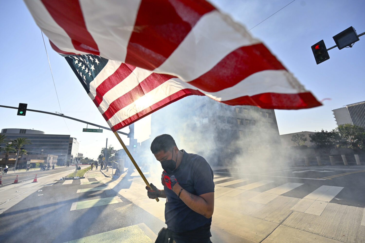 A protester raises the U.S. flag after police use tear gas and flash-bangs at the Federal Building ...