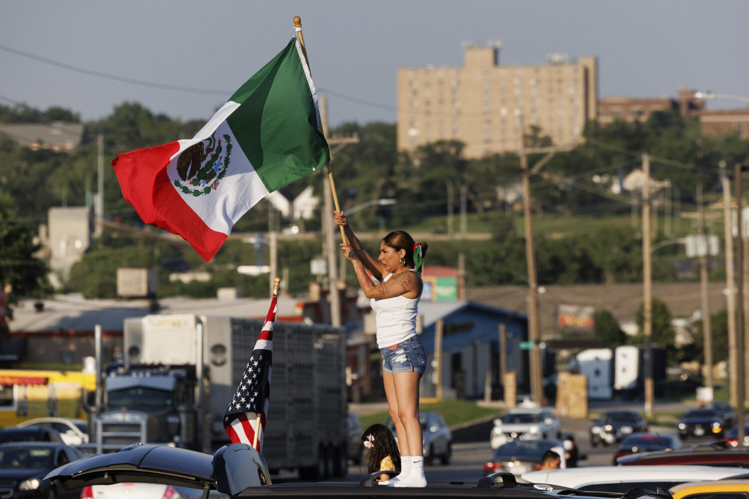 Brila Adauto of Omaha waves a Mexican flag as hundreds gather in after U.S. Immigration and Customs...