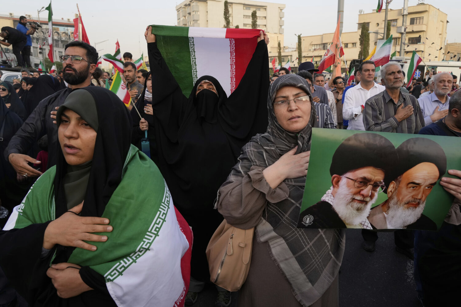 Iranian protesters hold their country's flags and a poster of Supreme Leader Ayatollah Ali Khamenei...
