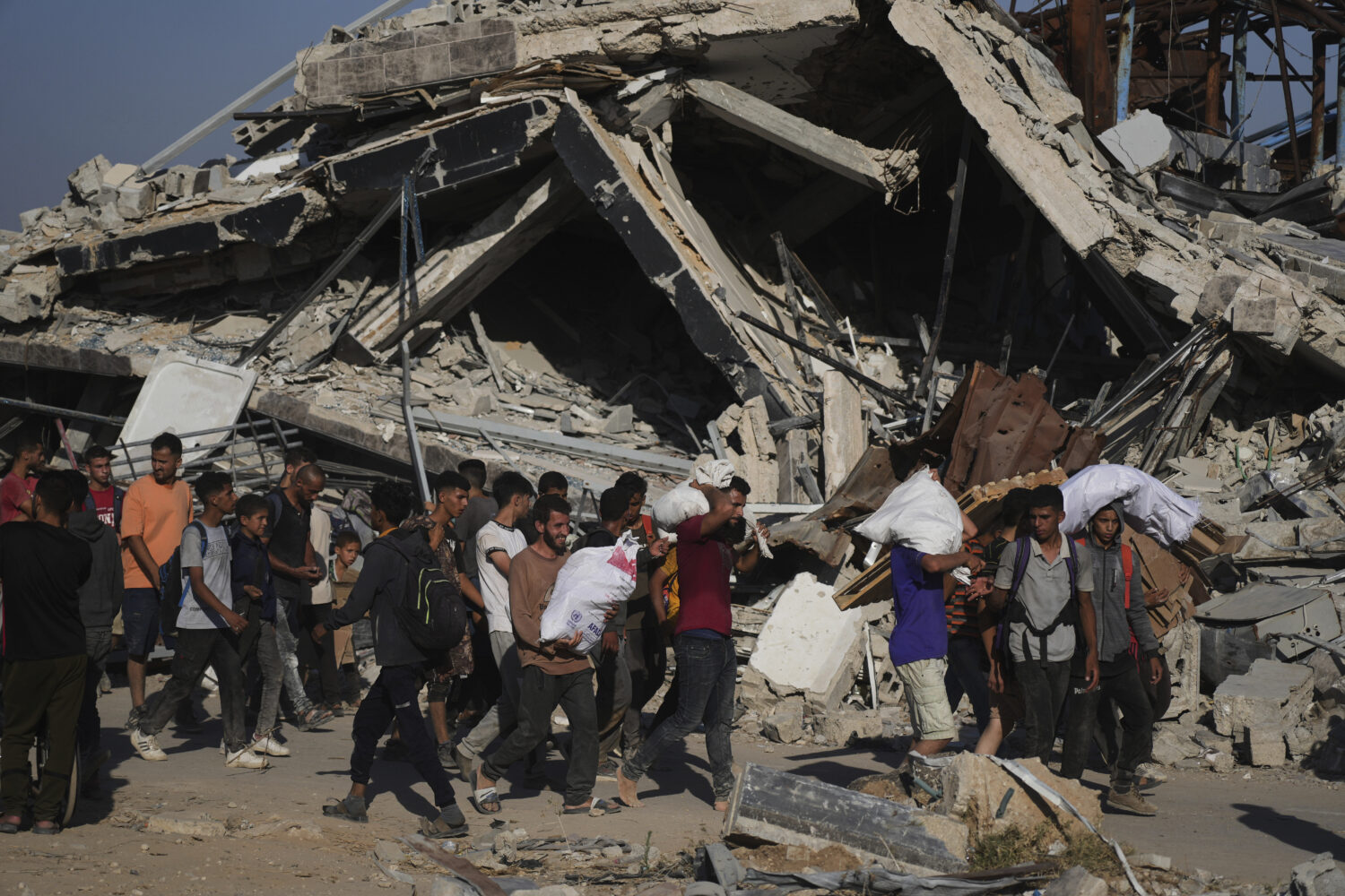 Palestinians carry humanitarian aid packages distributed by the Gaza Humanitarian Foundation operat...