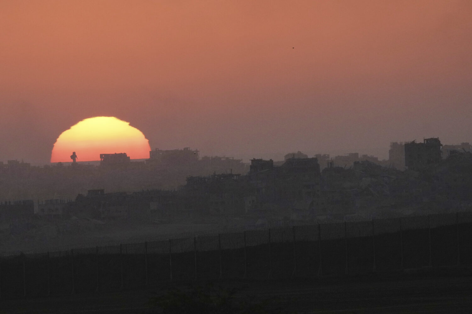 The sun sets behind destroyed buildings in the northern Gaza Strip near the Israel-Gaza border, sou...