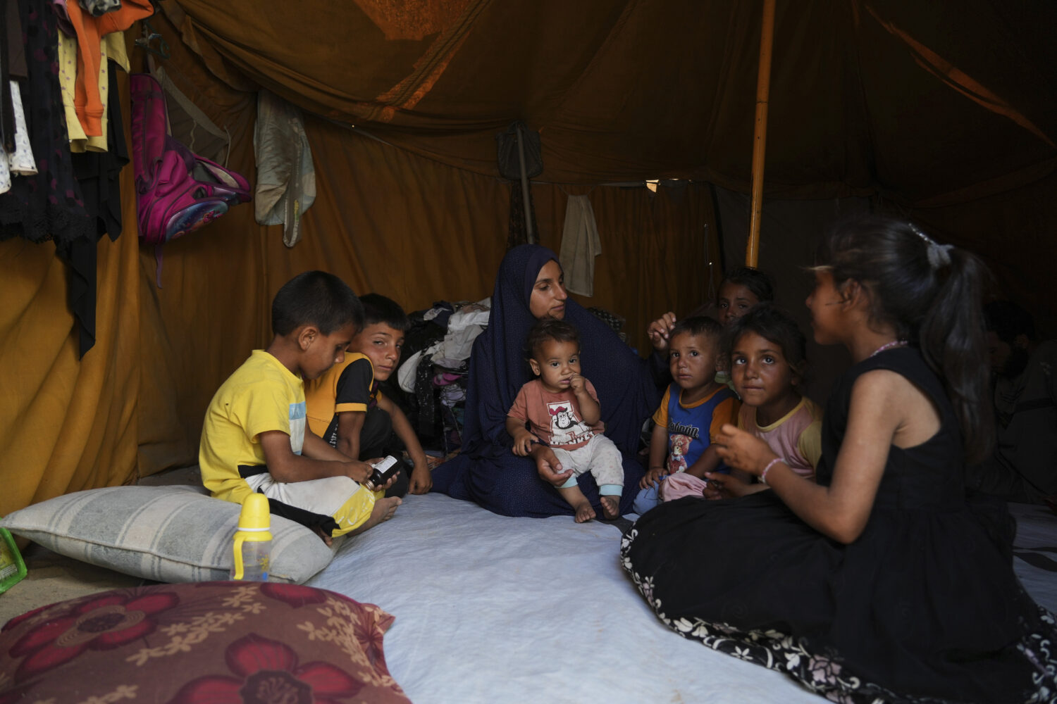 Maryam Abu Shaar, 29, sits with her children inside their tent at a camp for displaced Palestinians...