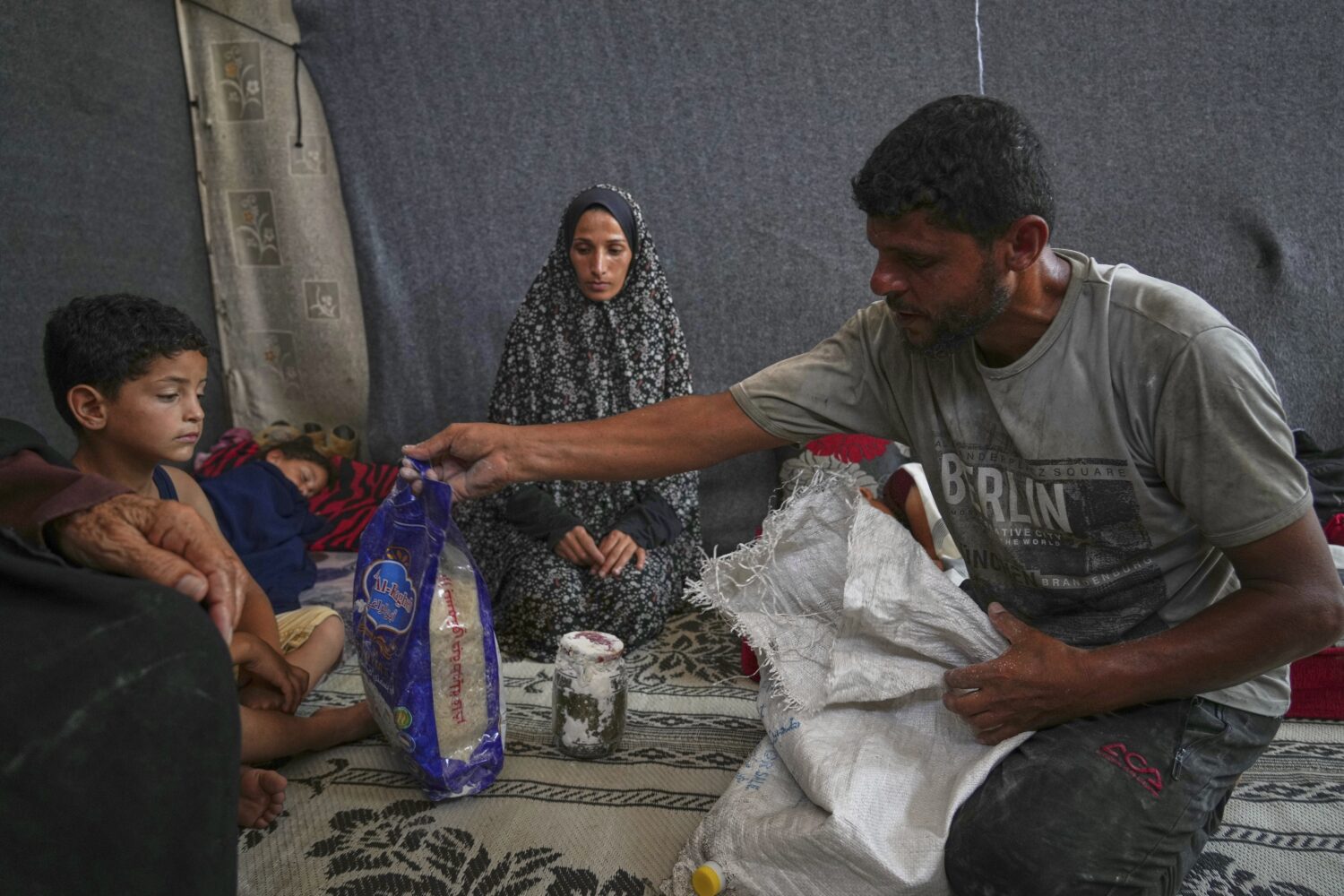 Omar al-Hobi, 43, from Rafah, unpacks a bag of food he collected at a distribution center run by pr...