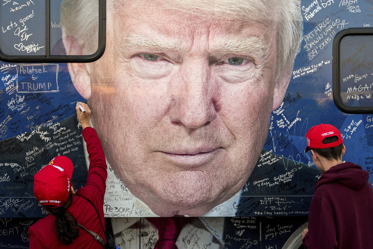 FILE - Supporters of Republican presidential nominee former President Donald Trump sign a bus befor...