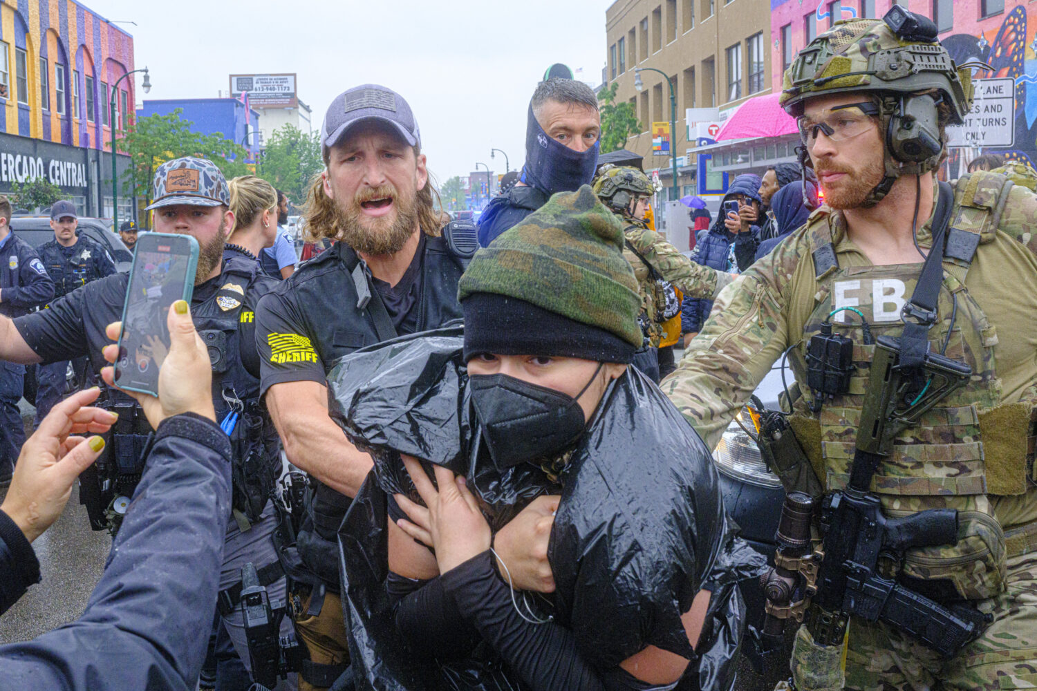 Community protesters confront law enforcement officers as federal agents conduct an operation in Mi...